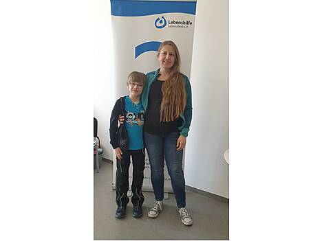Mutter und Sohn stehen vor Banner