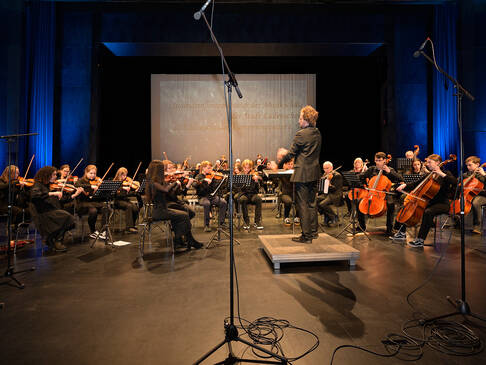 Ein Orchester auf der Bühne, sitzend.