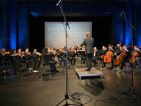 Ein Orchester auf der Bühne, sitzend.