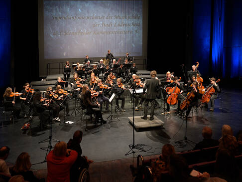 Ein Orchester auf der Bühne, sitzend.