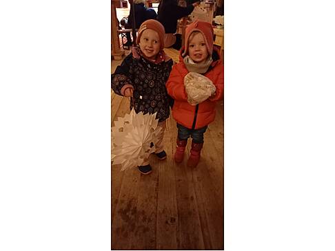 Zwei Kinder, eins mit einer Laterne und eins mit einer Waffel in der Alm.