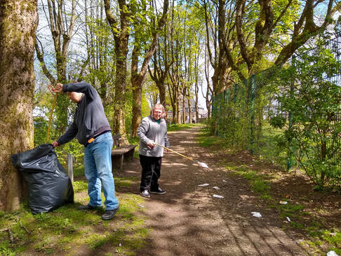 Zwei Personen sammeln Müll im Wald.