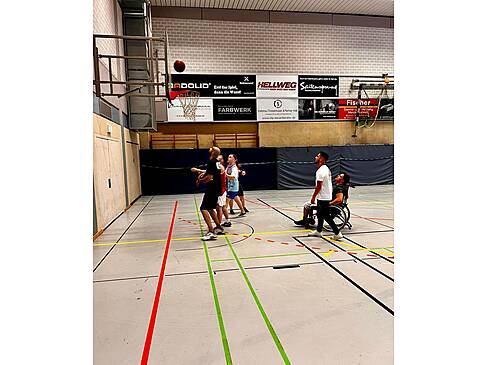 Basketballer mit und ohne Hilfsmittel auf einem Spielfeld.