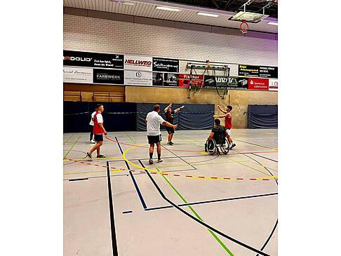 Basketballer mit und ohne Hilfsmittel auf einem Spielfeld.