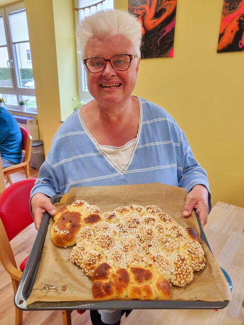 Eine Frau hält einen selbstgebackenen Kuchen in der Hand.