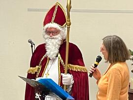 Eine Frau mit Mikrofon steht neben dem Nikolaus.