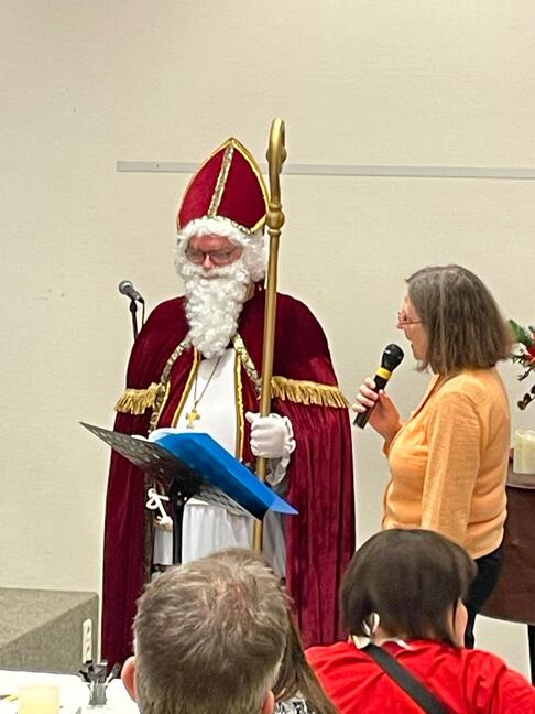 Eine Frau mit Mikrofon steht neben dem Nikolaus.