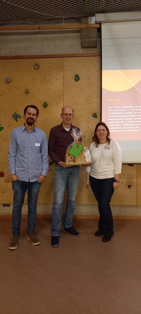 Auf einem Foto sieht an Thorbjörn Köpp, Sven Sieburg mit einem Geschenk und Stefanie Schröder