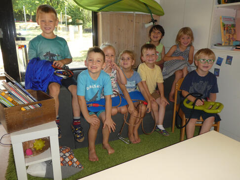 Viele Kinder sitzen im Gruppenraum auf einem Sofa.