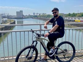 Herr Messam auf einem Fahrrad an einem Fluss
