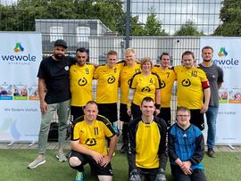 Eine Fussballmannschaft steht in gelben Lebenshilfetrickots zusammen.