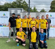 Eine Fussballmannschaft steht in gelben Lebenshilfetrickots zusammen.