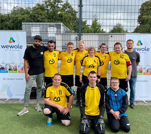 Eine Fussballmannschaft steht in gelben Lebenshilfetrickots zusammen.