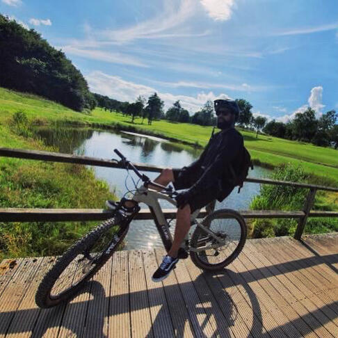 Ein Mann auf einem Mountainbike, vor einem Teich.