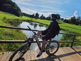 Ein Mann auf einem Mountainbike, vor einem Teich.