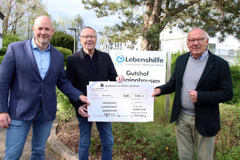 Drei Herren von der Lebenshilfe Lüdenscheid - Märkischer Kreis und dem Lions Club halten einen Check in der Hand.
