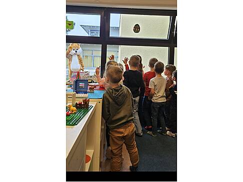 Viele Kinder stehen in einem Raum und schauen draussen zum Hasen.