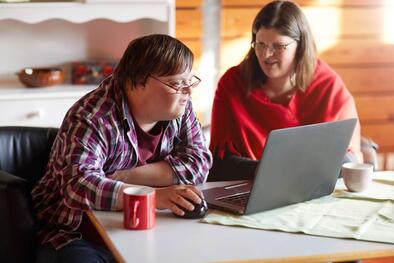 Ein Mann und eine Frau sitzen zusammen am Tisch vor einem Laptop.