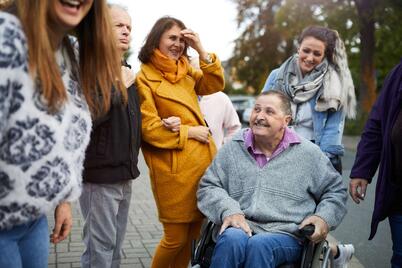 Mehrere Personen stehen draussen zusammen und lachen.
