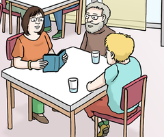 Drei Personen am Tisch einer hält ein Buch in den Händen.