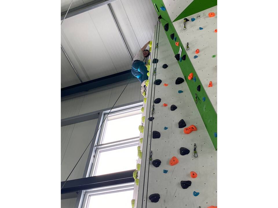 Kletterwand ganz oben ein junger Mensch