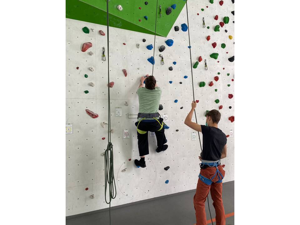 Ein Mensch an der Kletterwand ein anderer sichert ihn