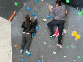 Zwei junge Menschen an der Kletterwand