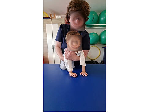 Frau hält Kind auf einem Tisch fest.