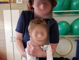 Frau hält Kind auf einem Tisch fest.
