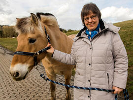 Eine Frau hält ein Pferd am Halfter