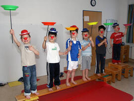 Sechs Kinder als Clowns verkleidet führen etwas vor.