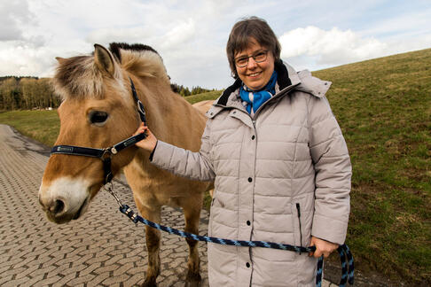 Eine Frau hält ein Pferd am Halfter