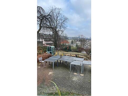 Gartenmöbel stehen auf der Fläche und im Hintergrund sieht man den Bagger