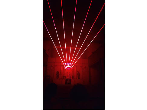 Von einem Gebäude scheinen rote Laserstrahlen.