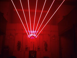 Von einem Gebäude scheinen rote Laserstrahlen.