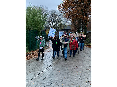 Einige Menschen mit Plakaten demonstrieren im Regen
