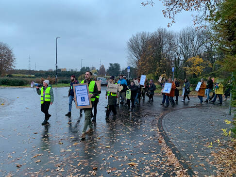 Einige Menschen mit Plakaten demonstrieren im Regen