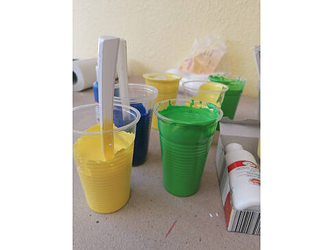 Becher mit grüner, gelber und blauer Farbe.