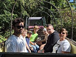 Eine Gruppe aus Kindern und Erwachsenen unterschiedlichen Alters blickt von einem Planwagen aus in die Kamera. Alle Beteiligten lächeln und genießen den gemeinsamen Ausflug in der Natur.