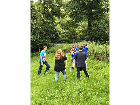 Mehrere Peronen stehen auf einer Wiese.