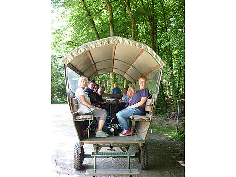 Mehrere Personen auf einem Planwagen.