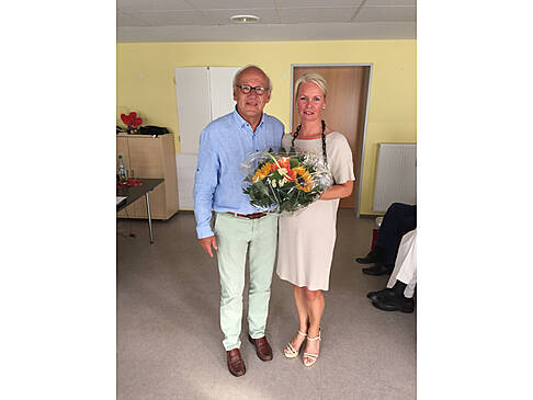 Ein Mann und eine Frau stehen nebeneinander, die Frau hat einen Blumenstrauß in der Hand.