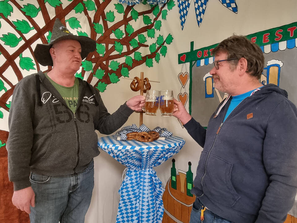 Zwei Männer stoßen mit Bier an.