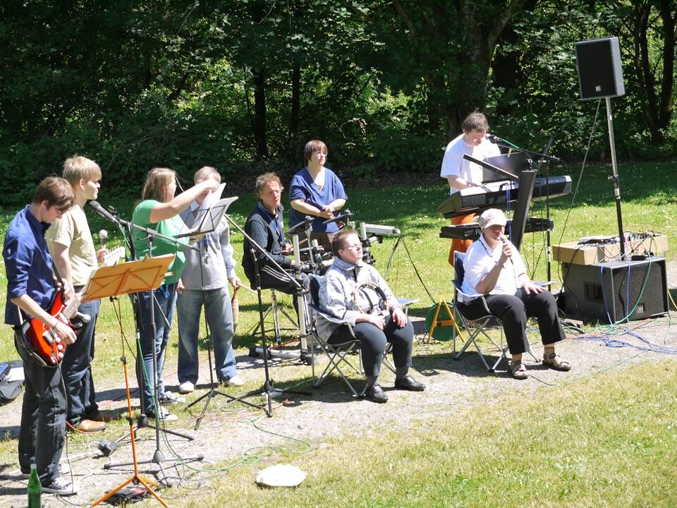 Eine Personengruppe macht draussen im Sonnenschein Musik.