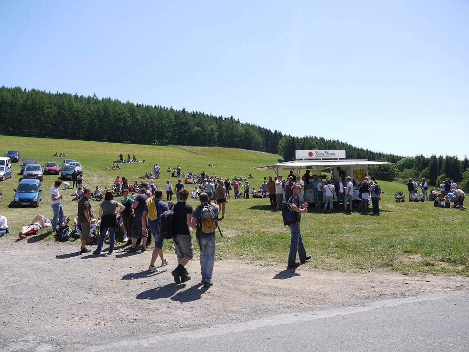 Mehrere Menschen und ein Bierwagen auf einer großen Wiese.