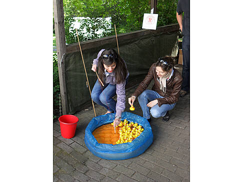 Zwei Frauen beim ENtenangeln an einem blauen Schwimmbecken.