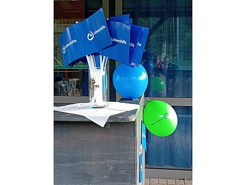 Lebenshilfe Fahnen und Ballons auf einem Stehtisch.