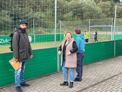 Drei Personen neben dem Spiellfeld.