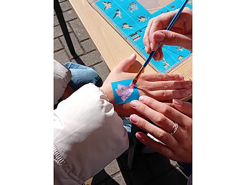 Eine Person bekommt etwas auf die Hand gemalt.