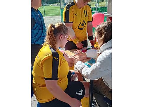 Eine Frau im Trikot sitzt an einem Tisch.